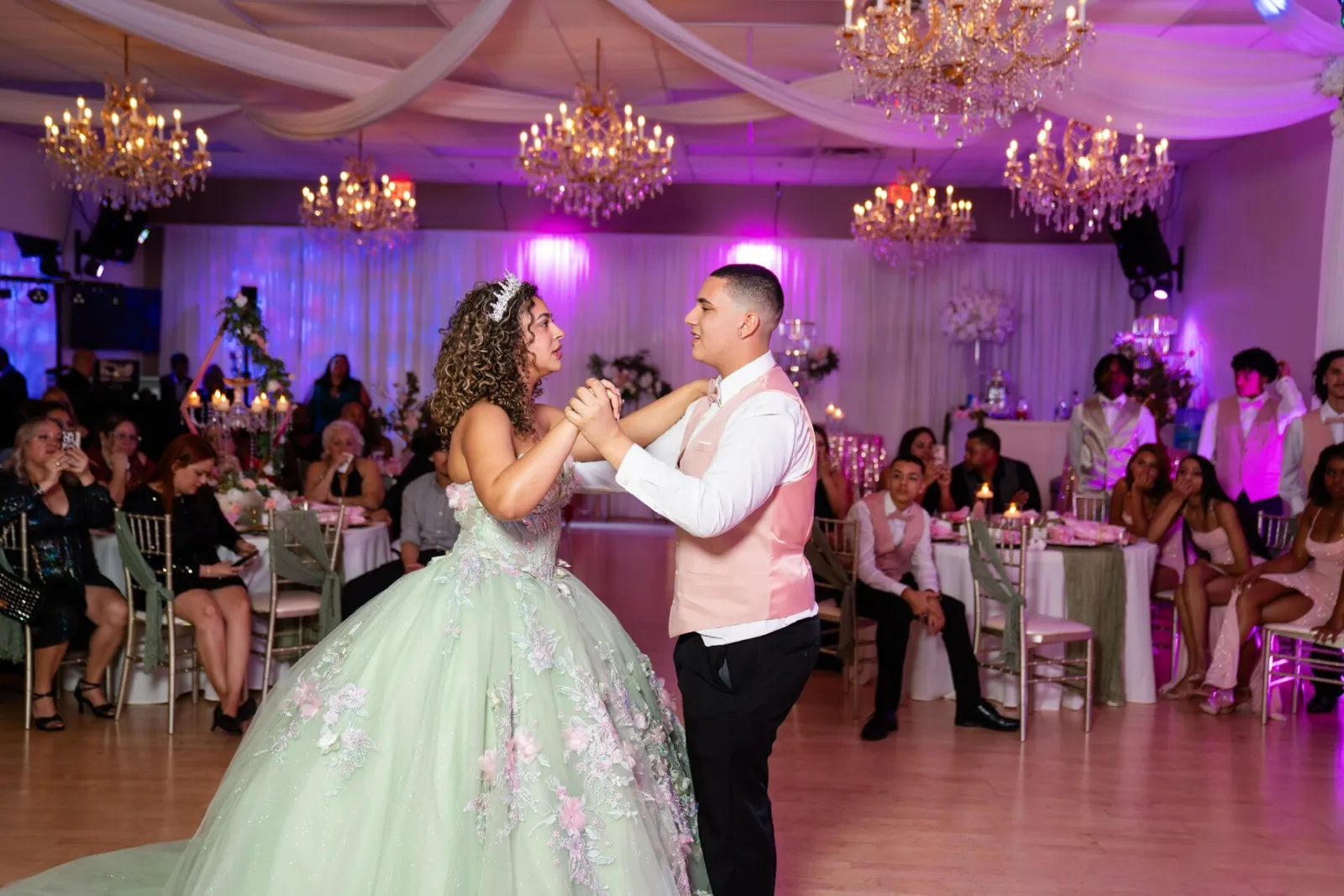 Quinceañera dance choreography moment in a mint dress under chandeliers and pink uplighting at Nencini Ballroom