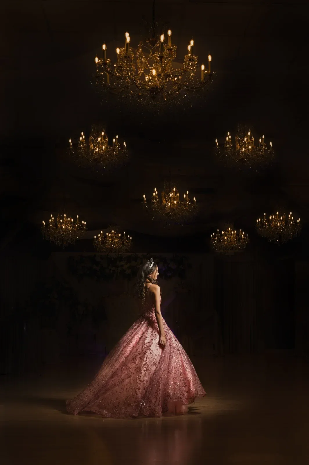 A quinceañera beneath the ballroom chandeliers