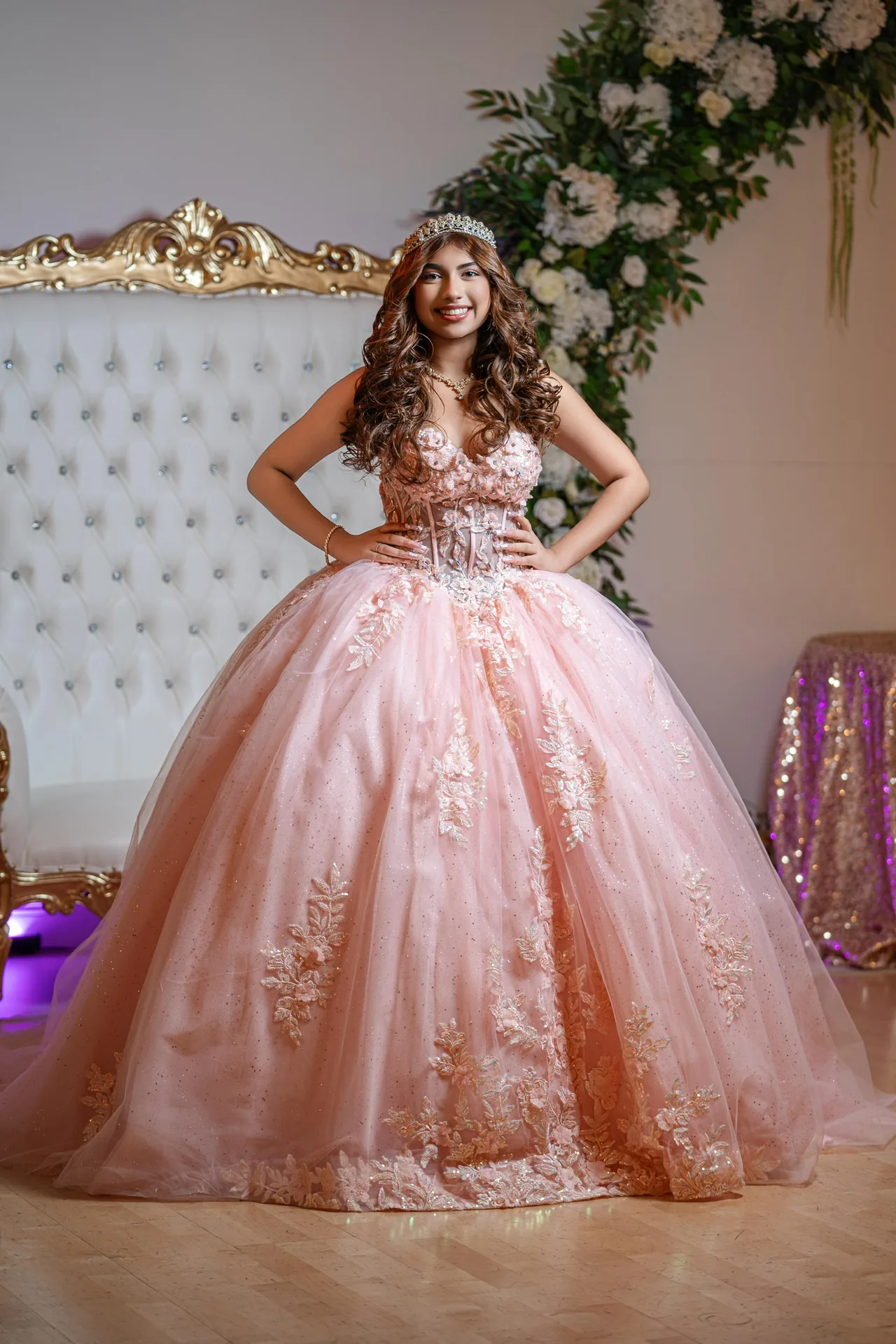 A Sweet 16 celebrant in a blush gown beside a floral arch at Nencini Ballroom