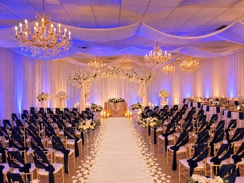 Navy chairs and a white aisle facing the floral ceremony backdrop at Nencini Ballroom