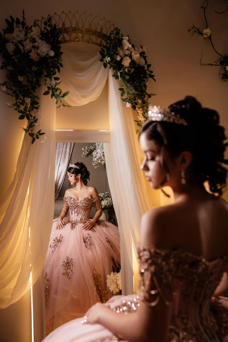Quinceañera in a pale pink gown reflected in the dressing-room mirror