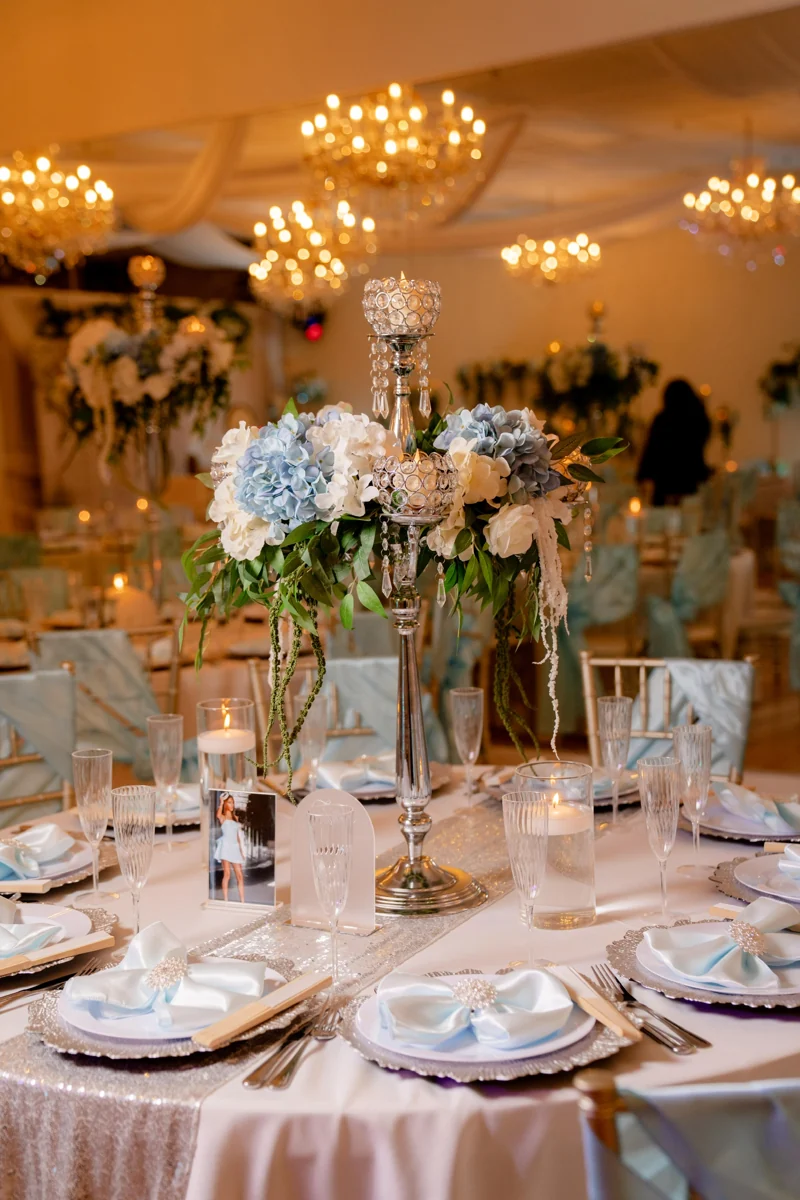 Blue and ivory wedding table with floral centerpiece and chandelier reflections